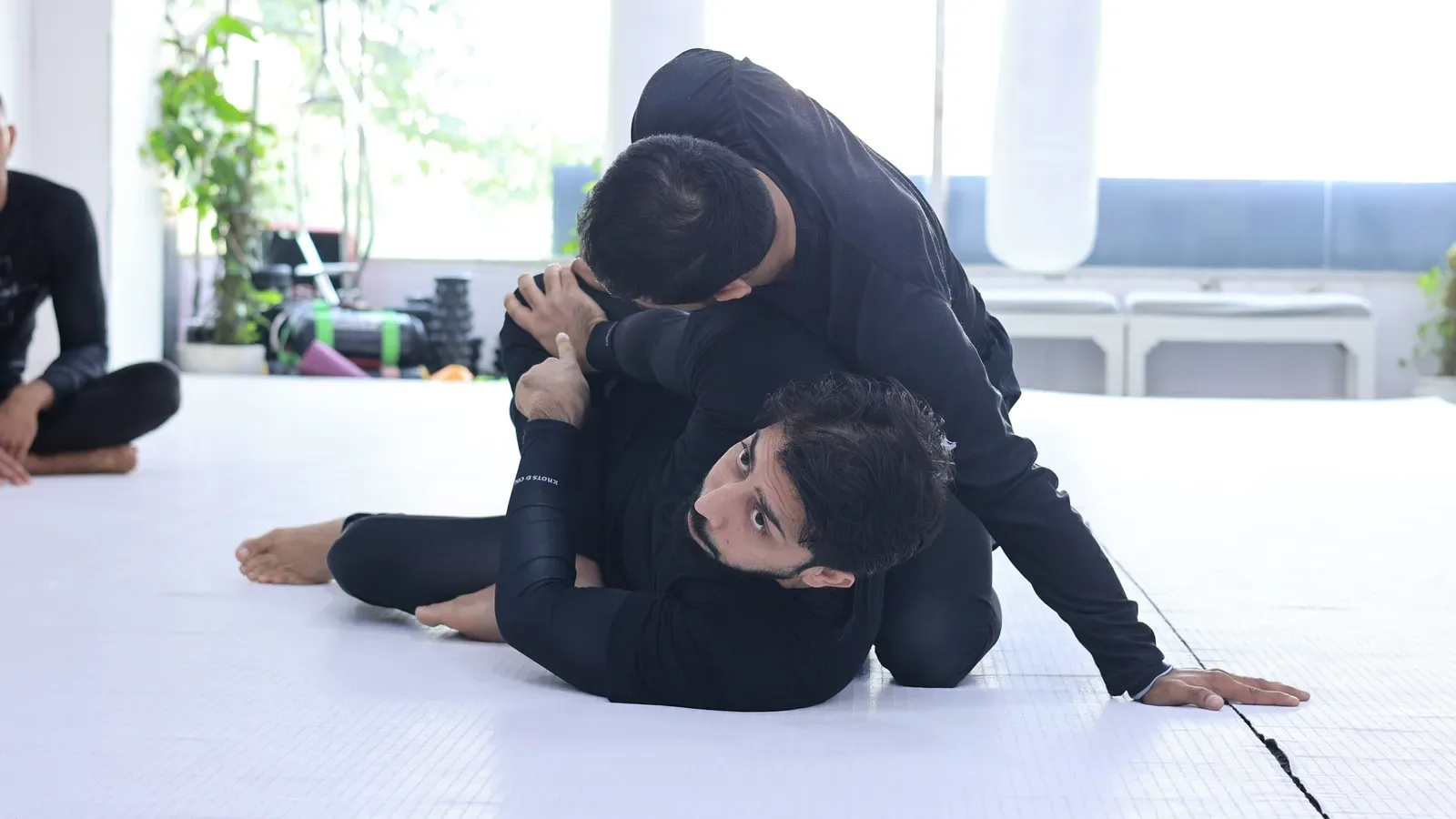 Straight arm against the knee while escaping the back mount in a Brazilian Jiu-Jitsu class in Delhi