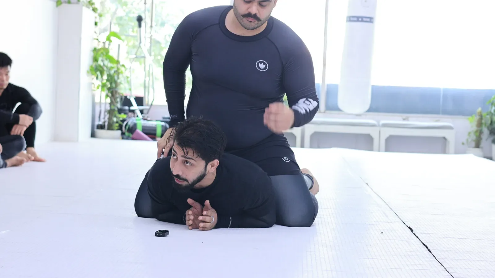 The common back mount mistake — both arms sandwiched under the chest — shown in a No-Gi BJJ class in New Delhi