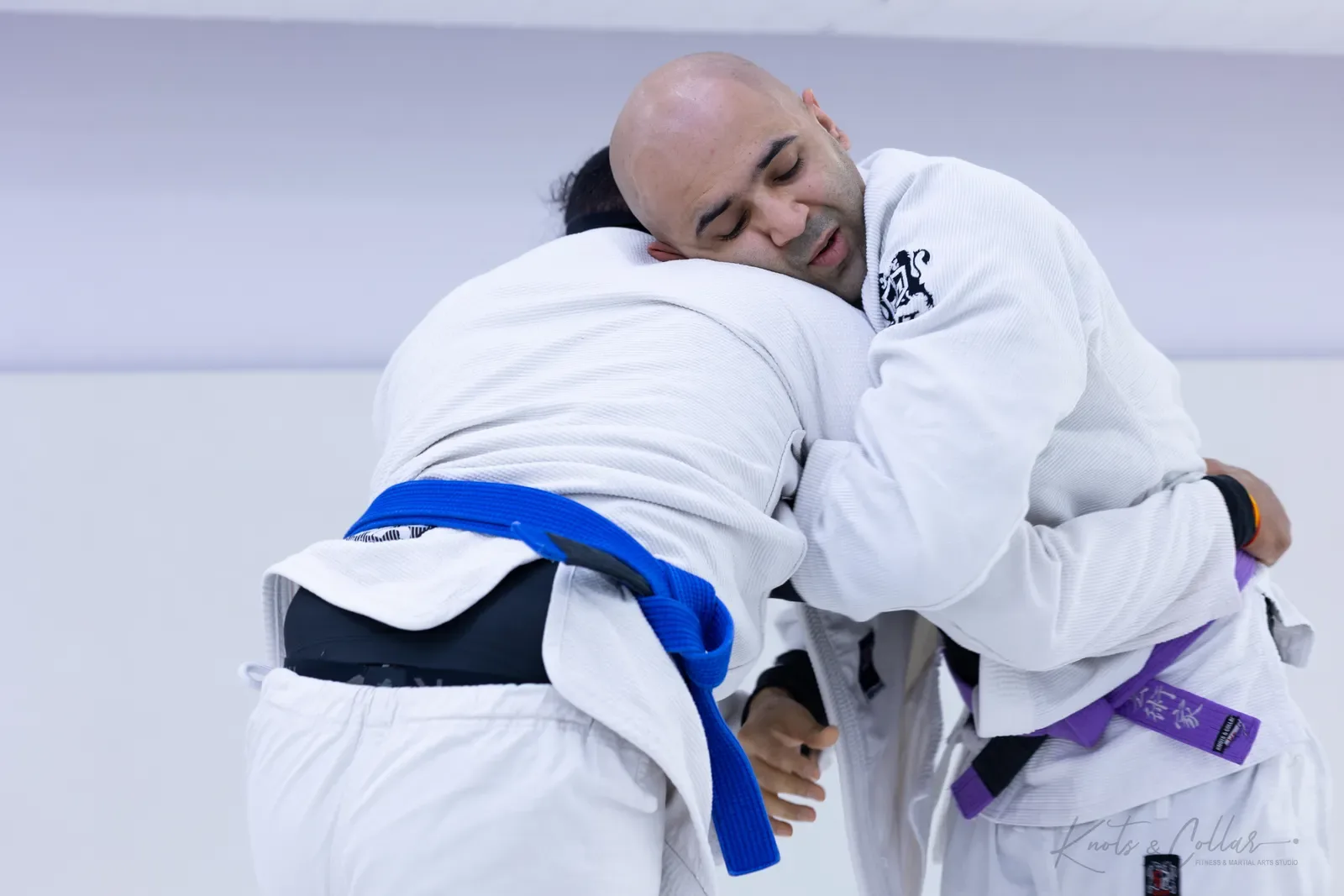 Two Brazilian jiu-jitsu training partners in a close clinch at Knots & Collar, Defence Colony, New Delhi