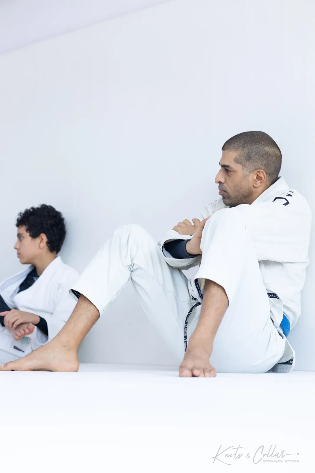 An adult and a young student resting between rounds during Brazilian jiu-jitsu training at Knots & Collar, Defence Colony, New Delhi