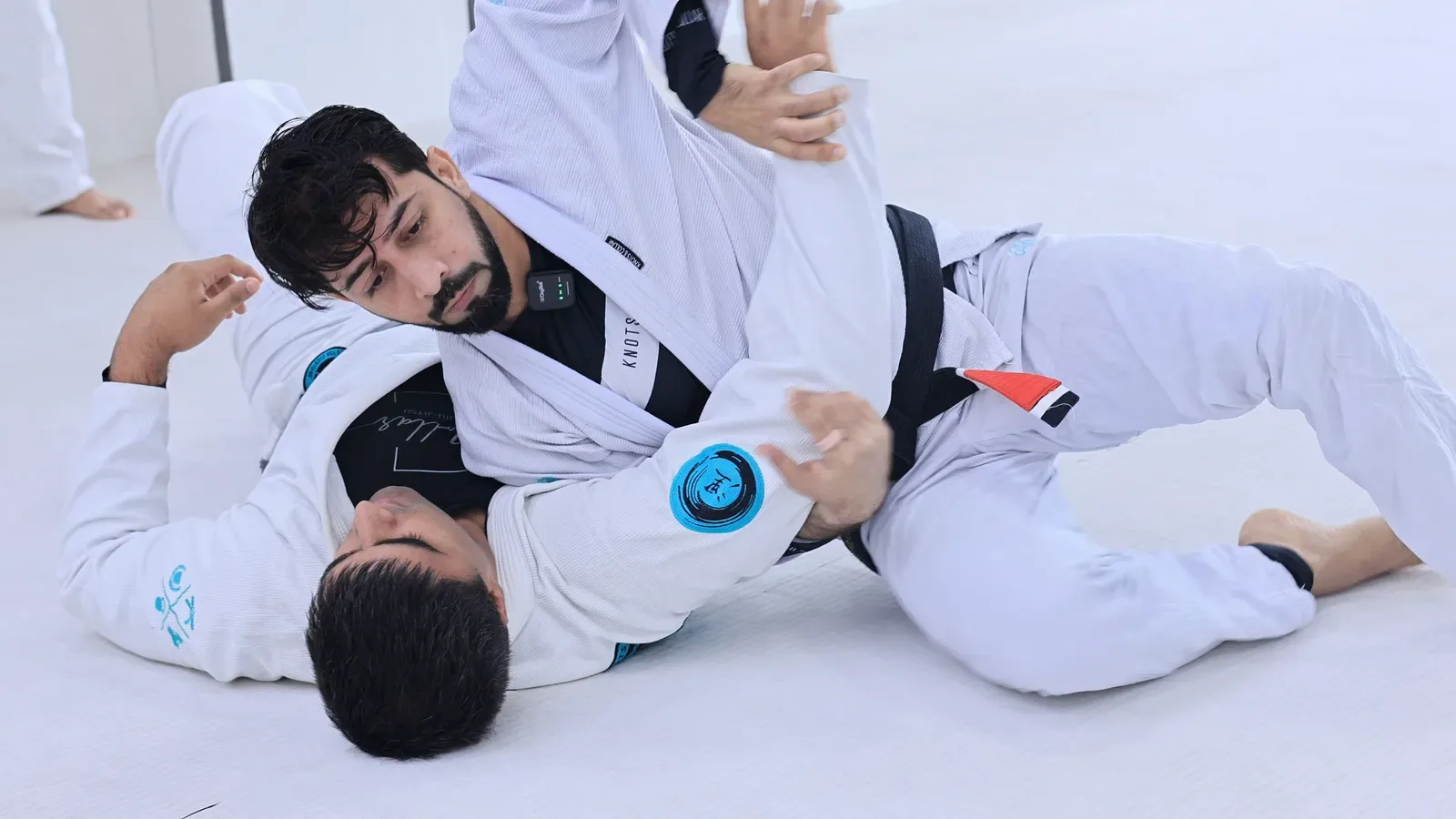 Chest pinning the bottom player's arm to the mat during a half guard pressure pass