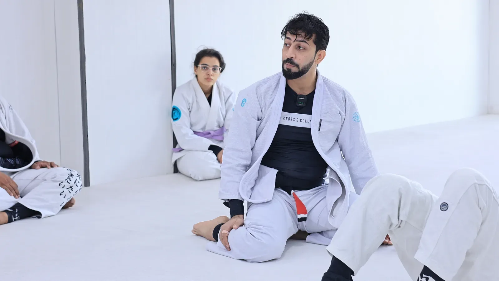 Black belt instructor sitting on the mat, talking students through a half guard passing lesson