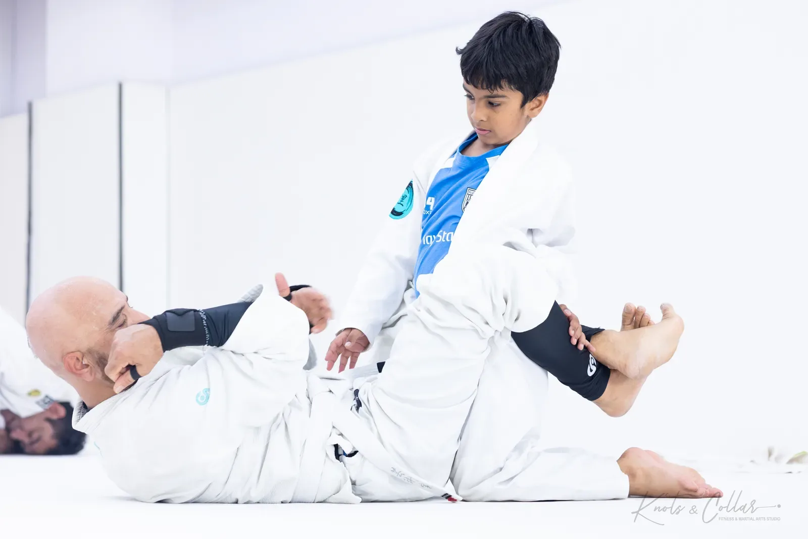A child working against an adult’s guard during Gi BJJ at Knots & Collar, Delhi