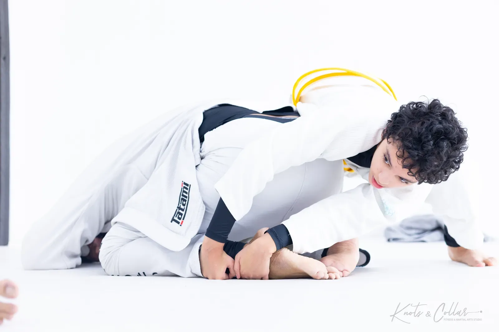 A young student controlling the leg in a scramble — Gi BJJ at Knots & Collar, Delhi