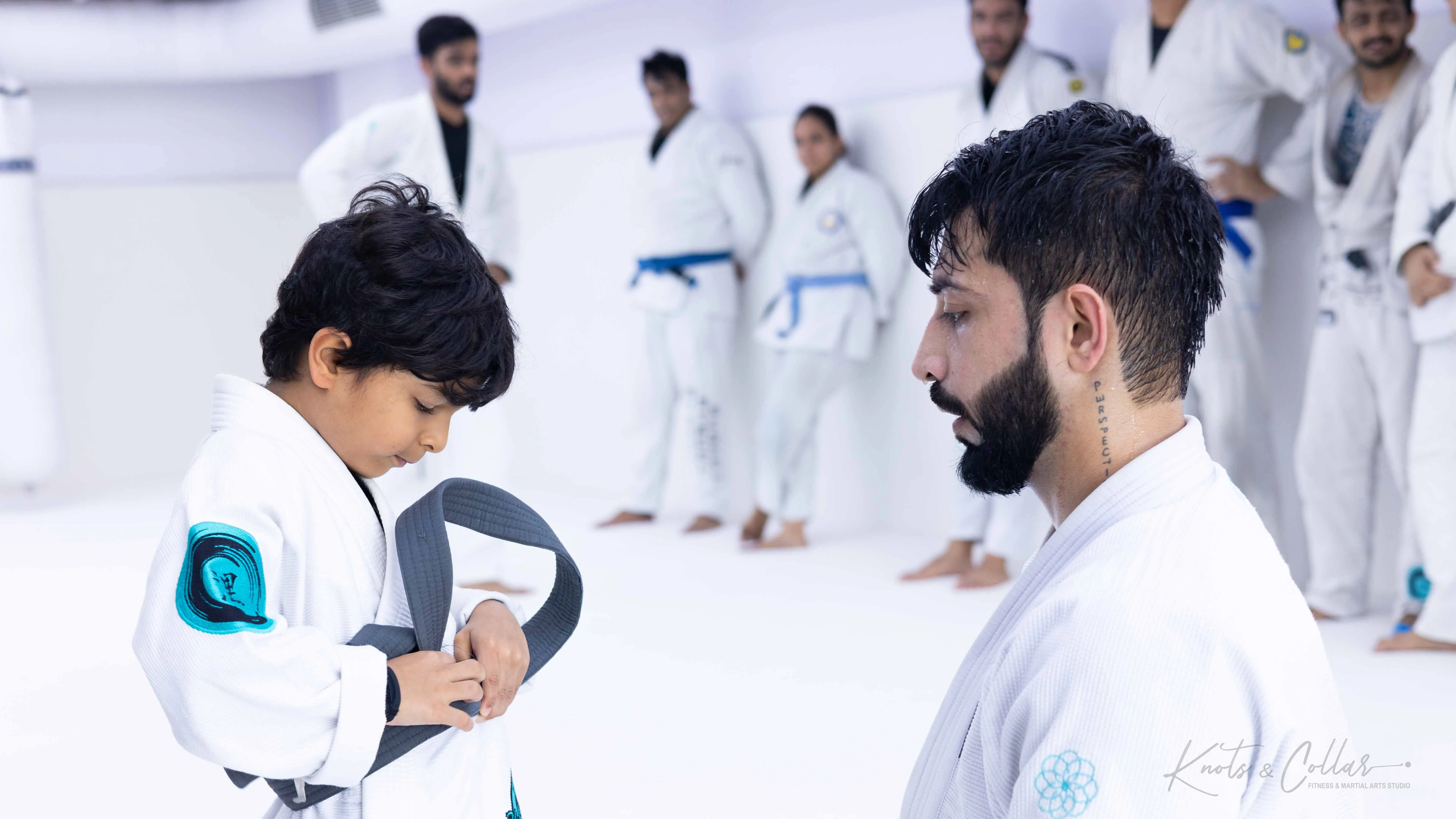 Instructor tying a belt for a young BJJ student at a legitimate academy in India