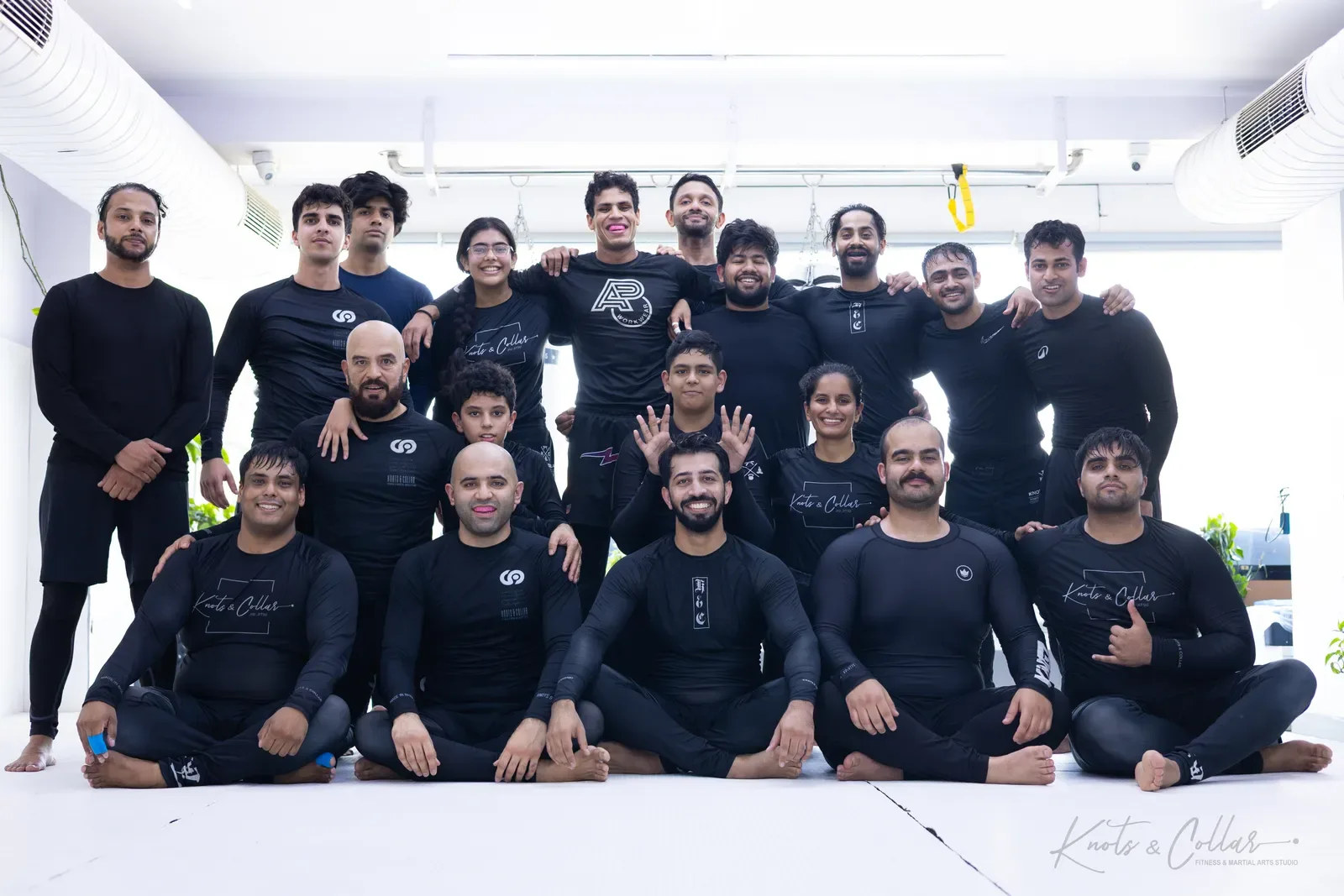 No-Gi BJJ class group photo at Knots & Collar, Defence Colony, New Delhi — adults and teenagers in rash guards after training Brazilian Jiu-Jitsu in India
