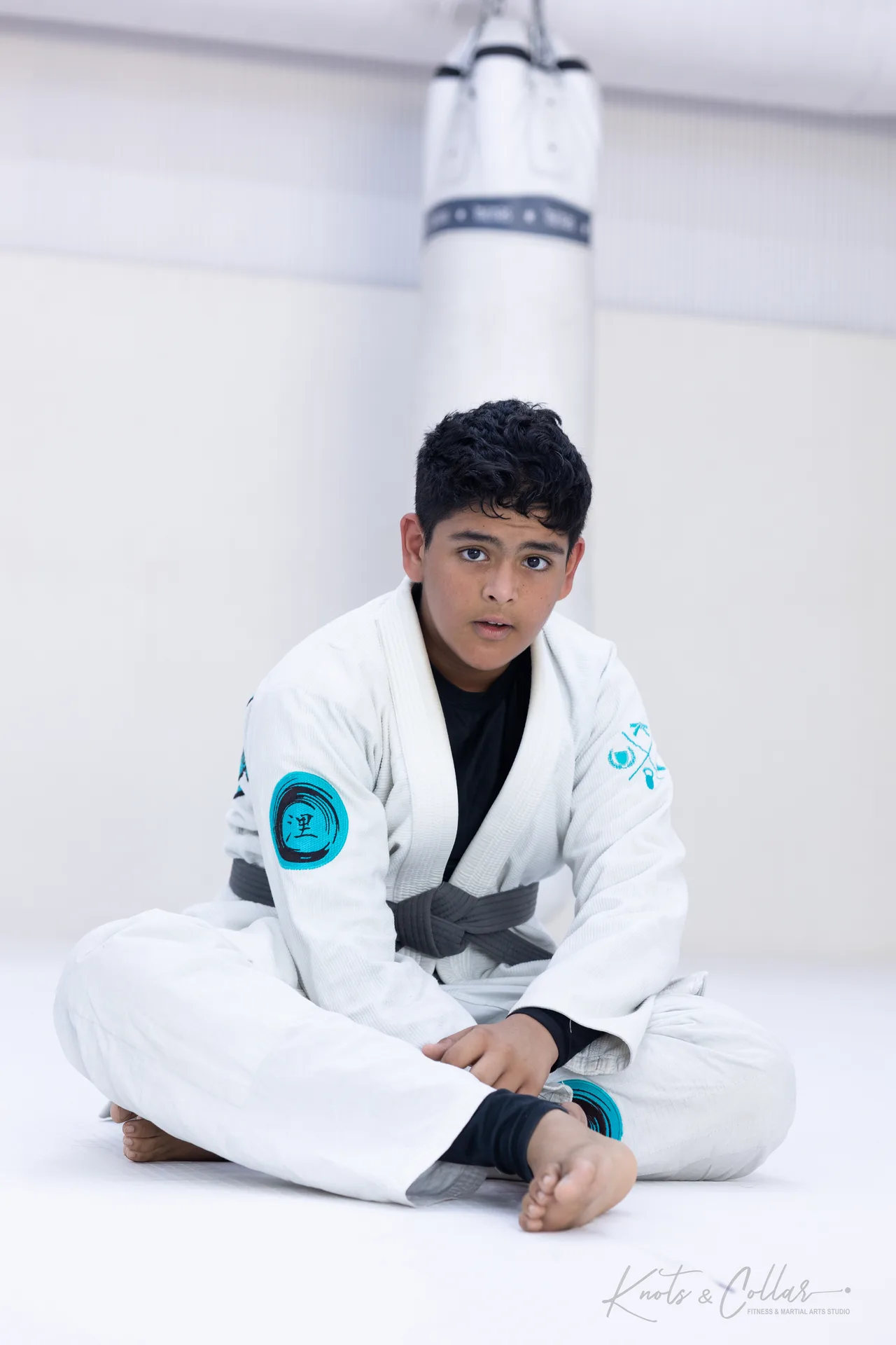 A teenage student in a white gi seated during a Brazilian Jiu-Jitsu class at Knots & Collar, Defence Colony, New Delhi