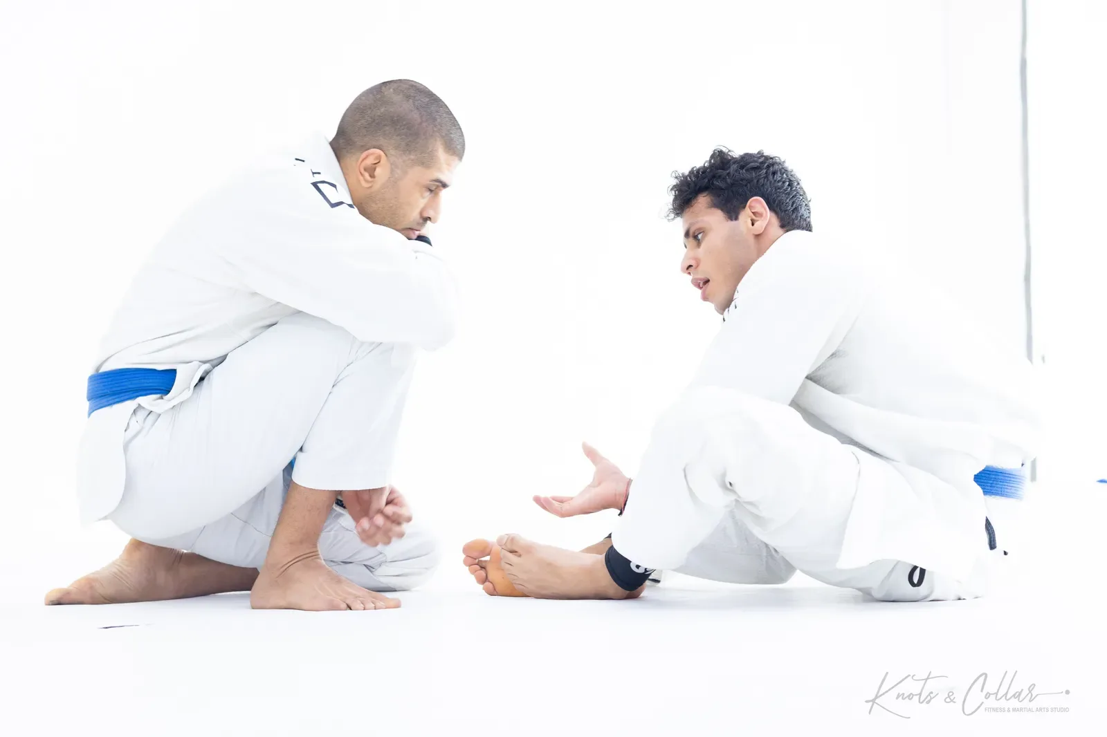 Two blue belts talking a position through between rounds at a Brazilian Jiu-Jitsu class in Delhi