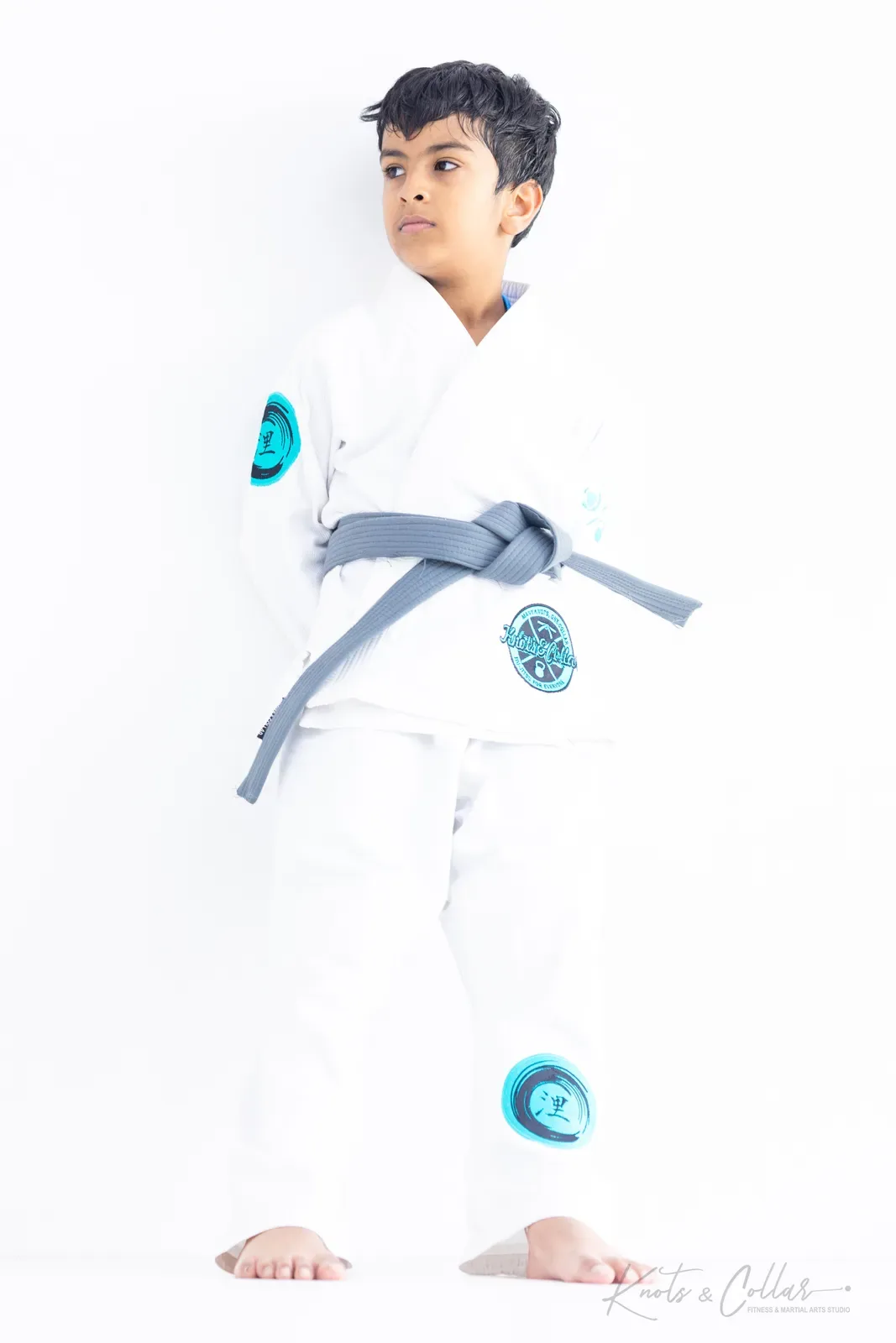 A young student in a white gi and grey belt at Knots & Collar kids Brazilian Jiu-Jitsu, an activity for children visiting Delhi