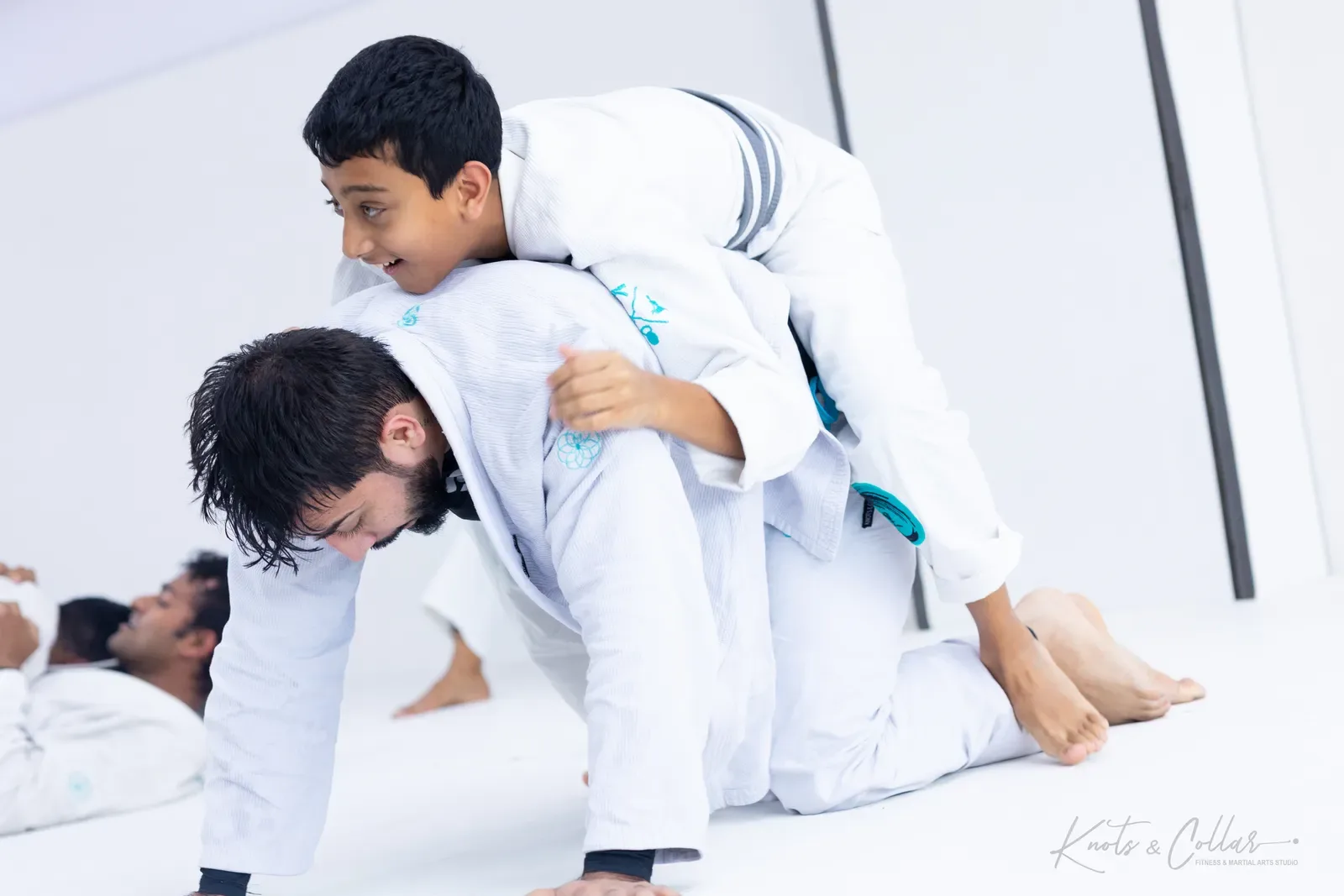A child climbing on to an adult&rsquo;s back during a playful Brazilian Jiu-Jitsu round at Knots & Collar in Delhi — kids activities in New Delhi